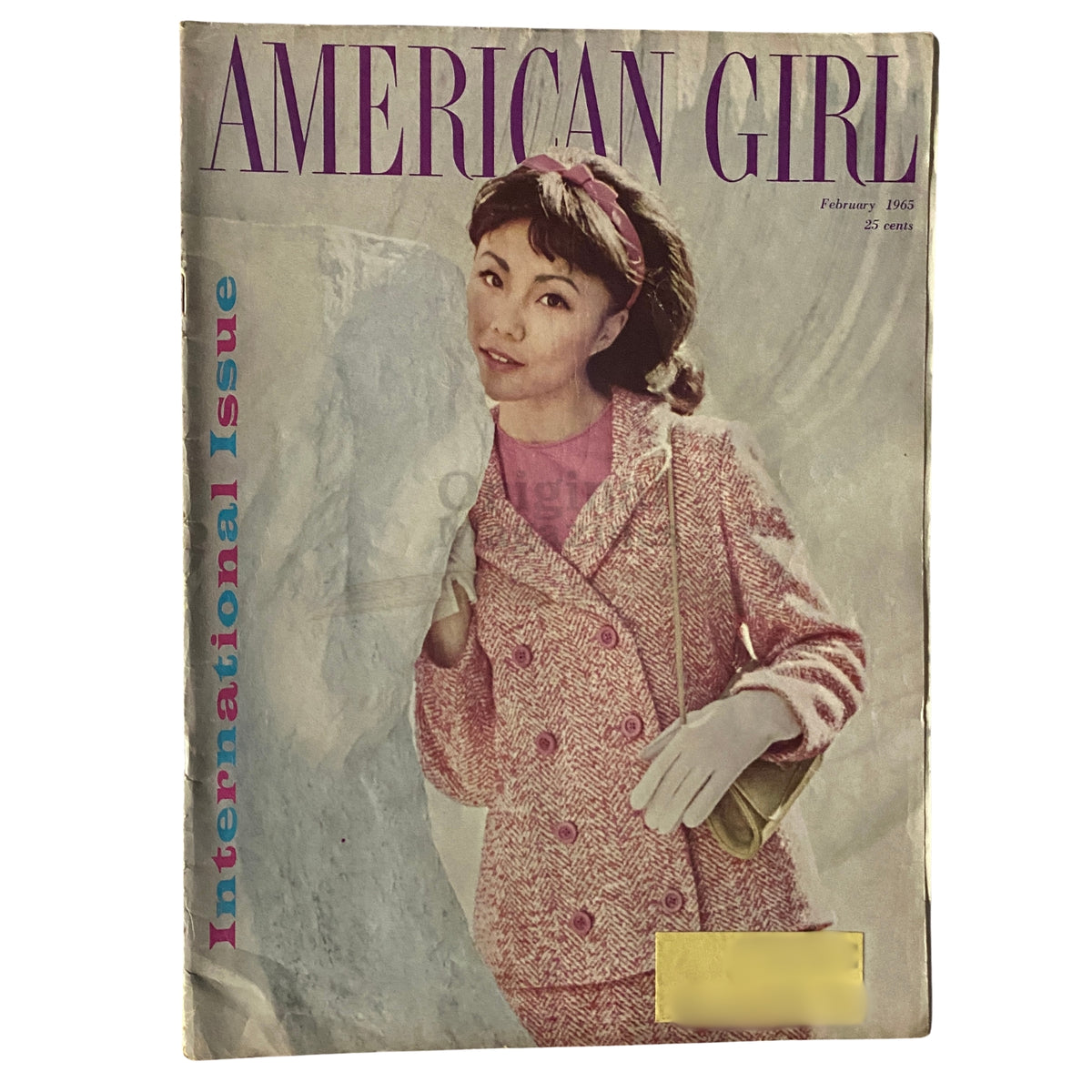 Cover of American Girl Magazine February 1965 featuring the title 'American Girl' and the subtitle 'International Issue'. The image shows a young woman wearing a stylish pink and white coat with gloves, embodying 1960s fashion.