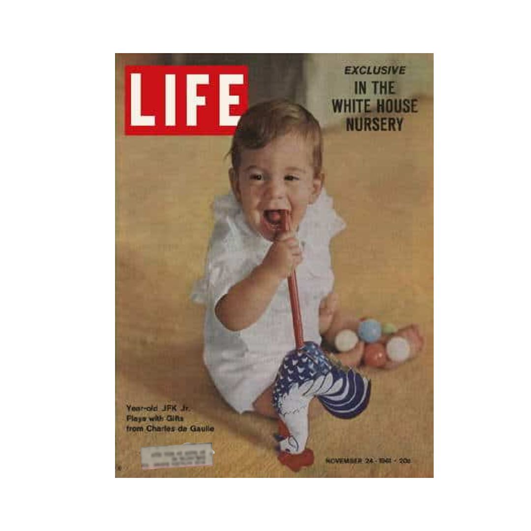 Life Magazine cover from November 24, 1961, featuring John F. Kennedy Jr. celebrating his first birthday, sitting on the floor with a playful expression and holding a toy, surrounded by colorful balls.