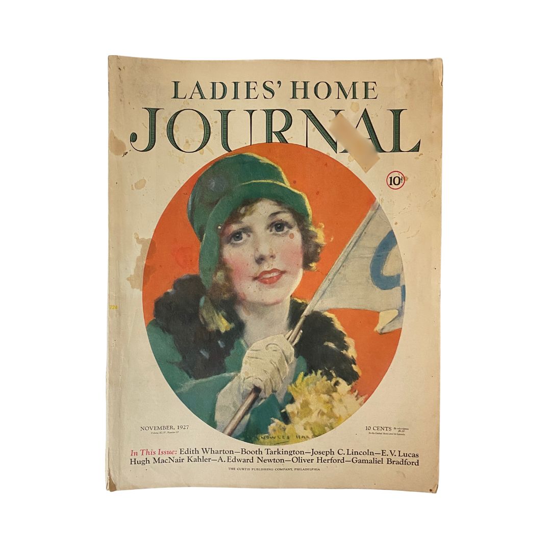 Ladies' Home Journal Magazine November 1927 cover featuring a vintage illustration of a woman smiling with a flag, emblematic of the era's art style.