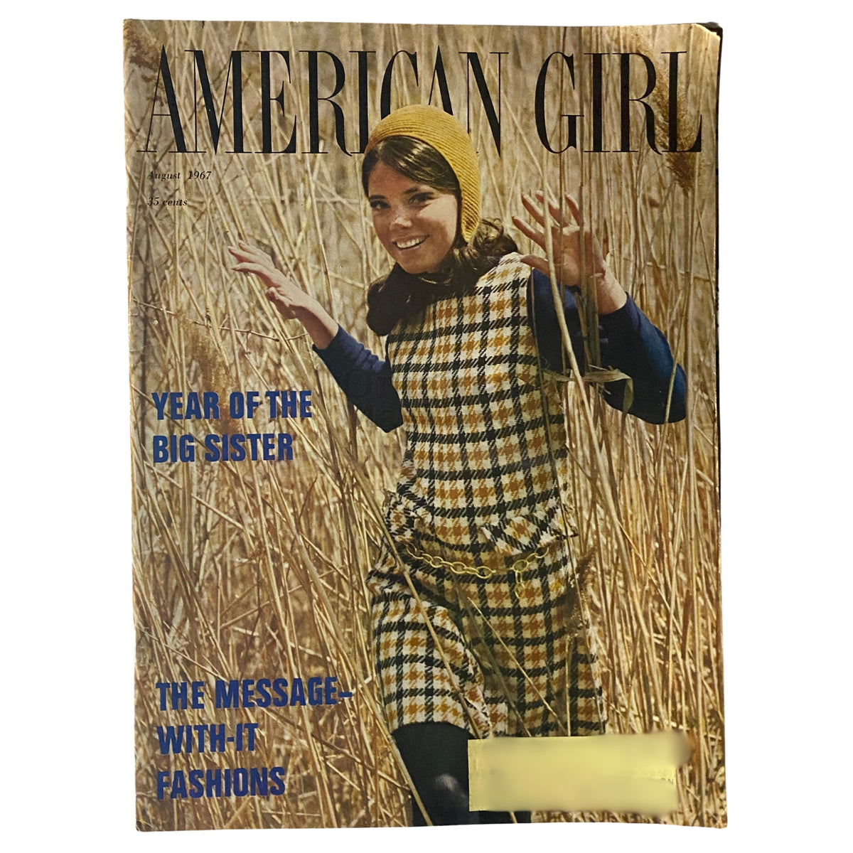 Cover of American Girl Magazine, August 1967, featuring a girl in a plaid dress amidst tall grass, highlighting the theme 'The Message-With-It Fashions'.