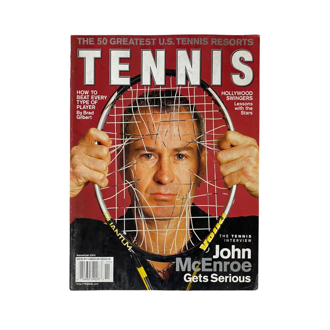 Tennis Magazine November 2002 featuring John McEnroe on the cover, portraying him holding a tennis racket with a serious expression, symbolizing his competitive nature.