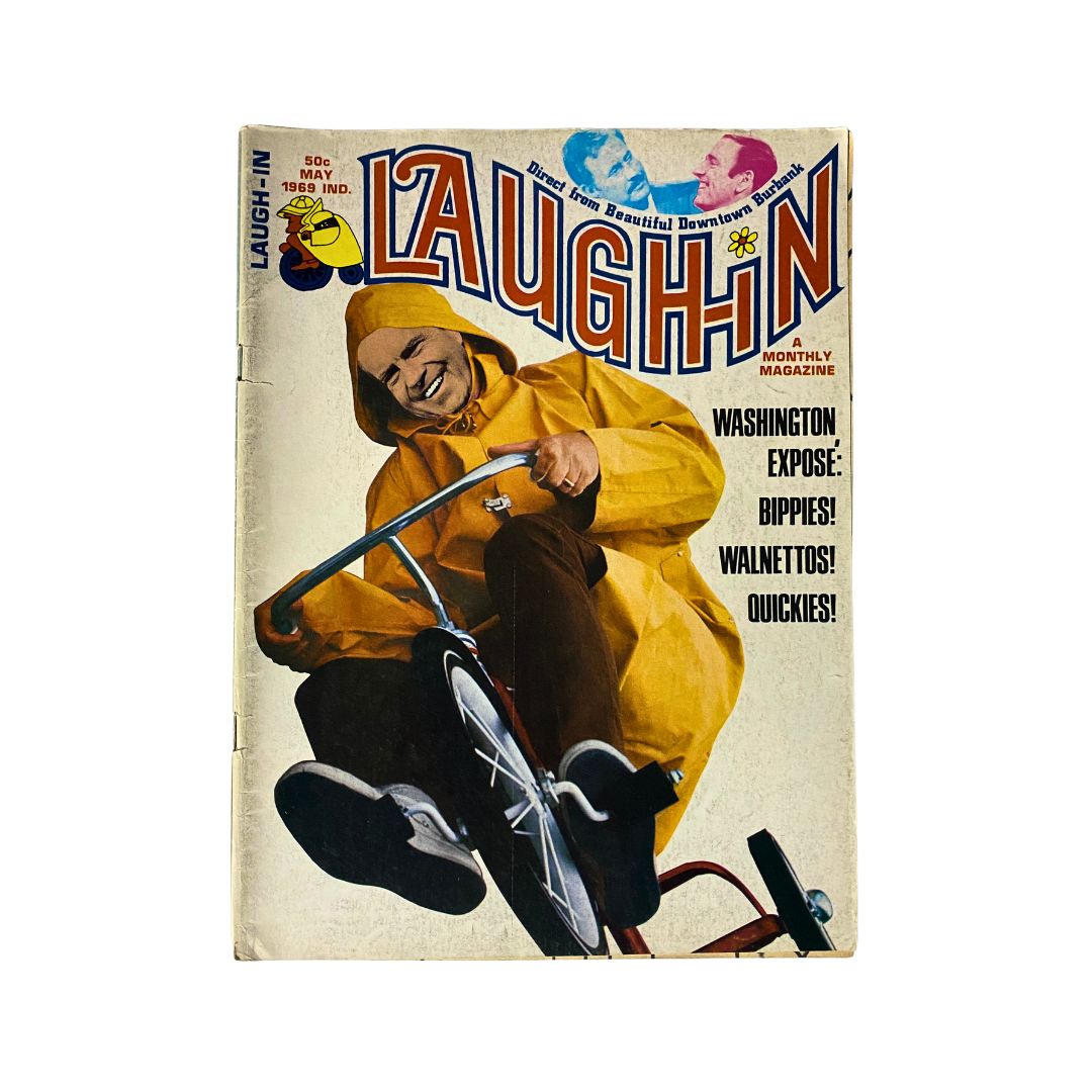 Cover of the VTG Laugh-In Magazine from May 1969 featuring a smiling individual in a yellow raincoat riding a tricycle, with the title 'LAUGH-IN' prominently displayed and topics like 'Washington Exposé' and 'Bippies' highlighted.