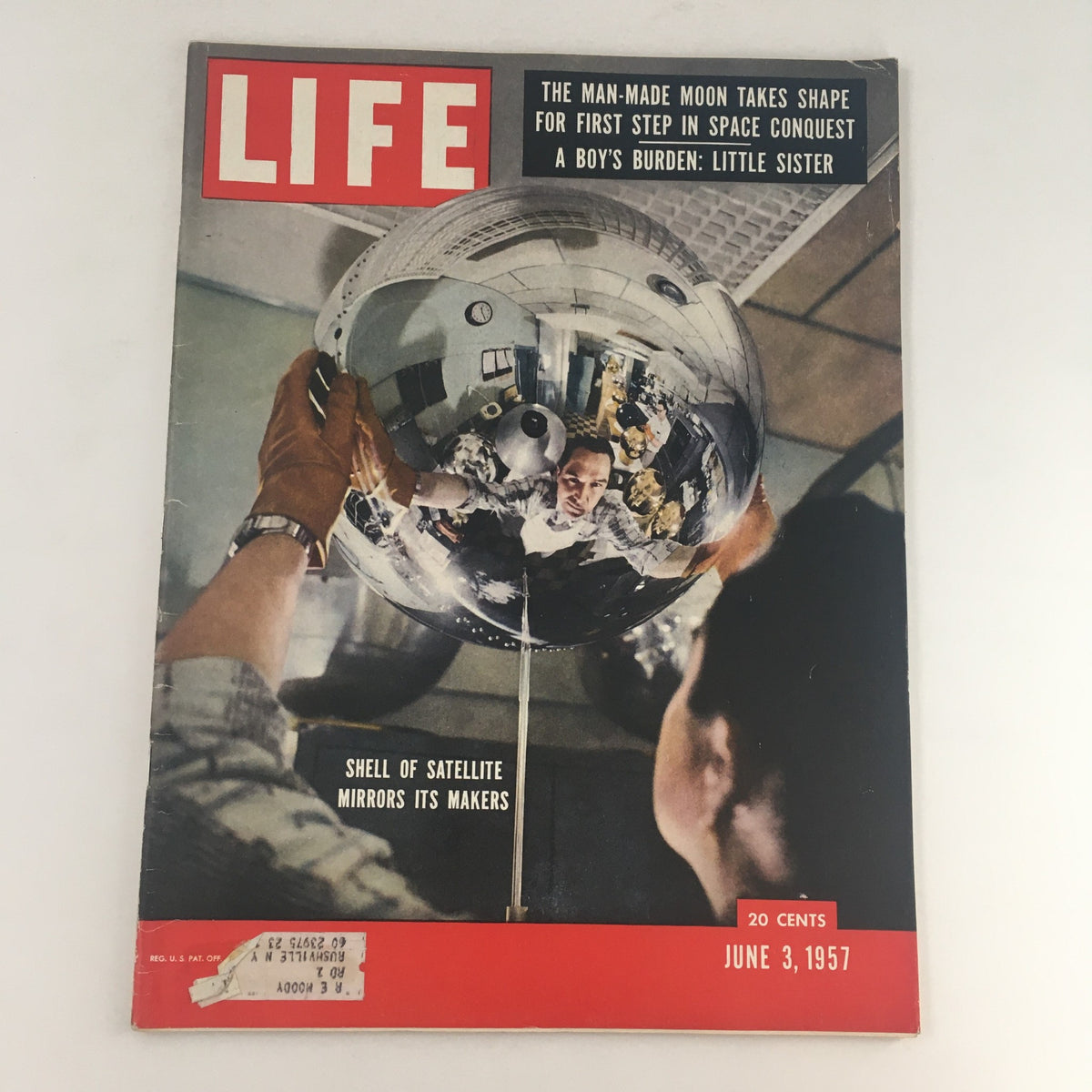 Cover of Life Magazine from June 3, 1957 featuring the title 'Shell of Satellite Mirrors Its Makers & A Boy's Burden.' The image showcases a man working with a reflective satellite shell, emphasizing technological advancements of the era.