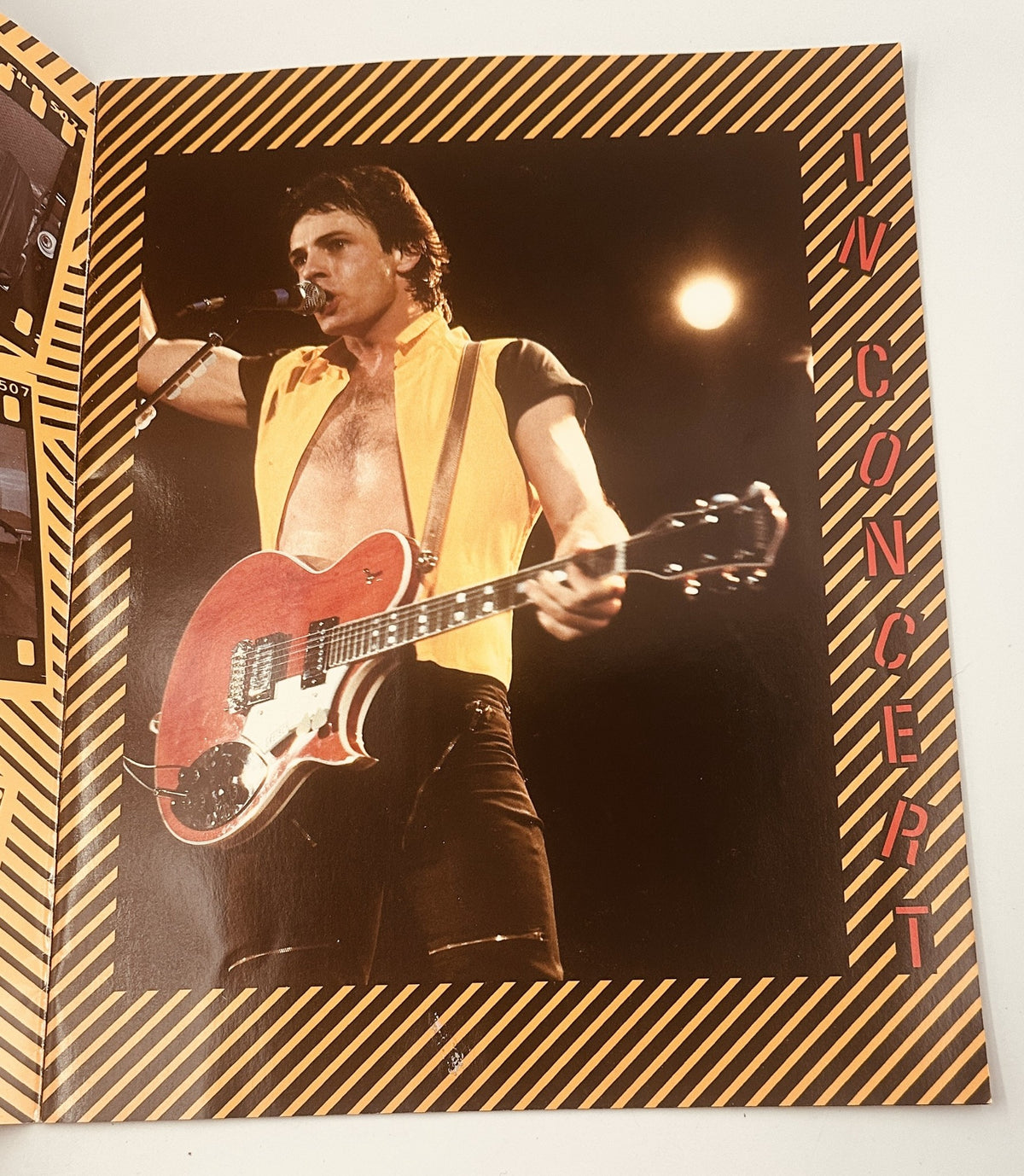 In-concert photo from the 1982 Sweat For Success Tour showcasing Rick Springfield performing energetically with a red guitar, highlighting his dynamic stage presence.