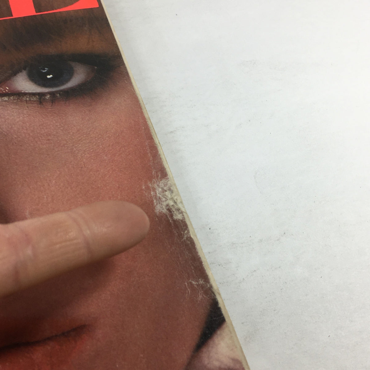 Detailed view of the Vogue Magazine March 1983 cover showing minor wear and tear near the model's eye, highlighting the magazine's vintage condition.