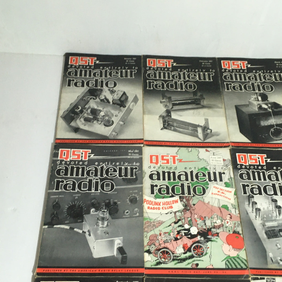 Lot of 12 Complete January to December 1957 QST Amateur Radio magazines displayed with an emphasis on their vintage designs and articles reflecting the era's technological advancements.