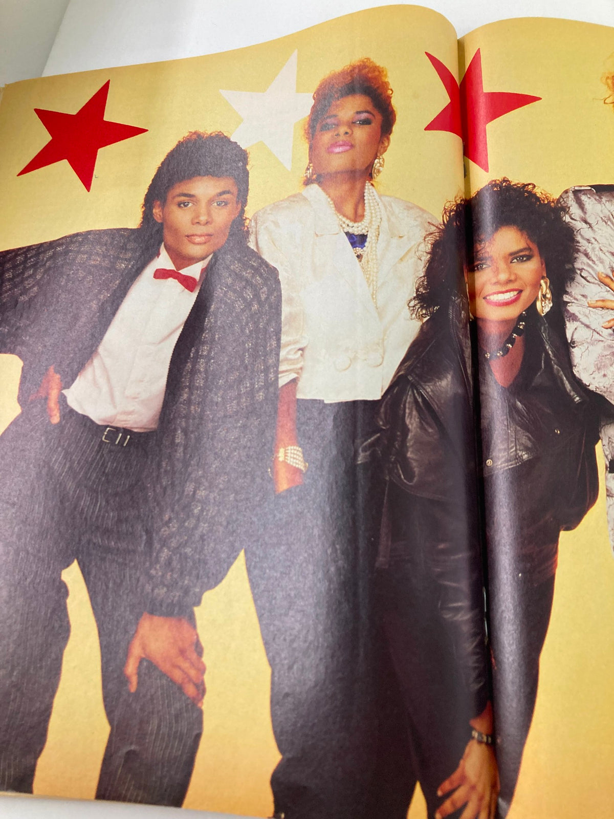 Inner spread of the Vintage Lookin Magazine May 10 1986 Issue showcasing three individuals in vibrant fashion outfits against a bright background with star graphics.