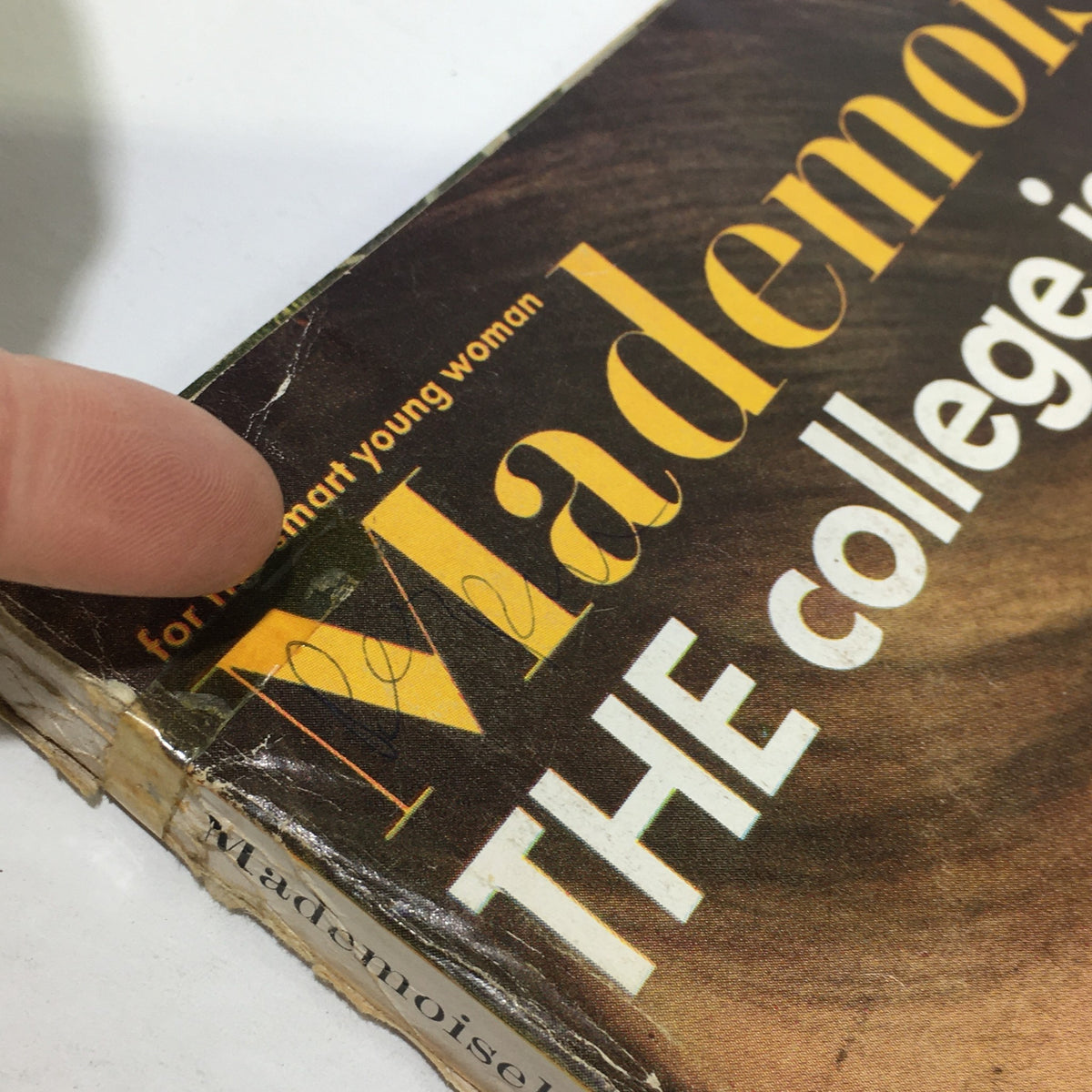 Close-up of the vintage Mademoiselle Magazine from August 1965, highlighting the worn cover with visible marks and a finger pointing at the title.