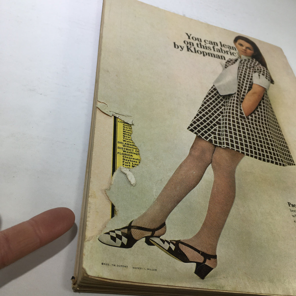 Back cover of the VTG Mademoiselle Magazine: August 1967 - College Issue, featuring a model in a checkered dress and a torn edge, showcasing vintage fashion advertisements.