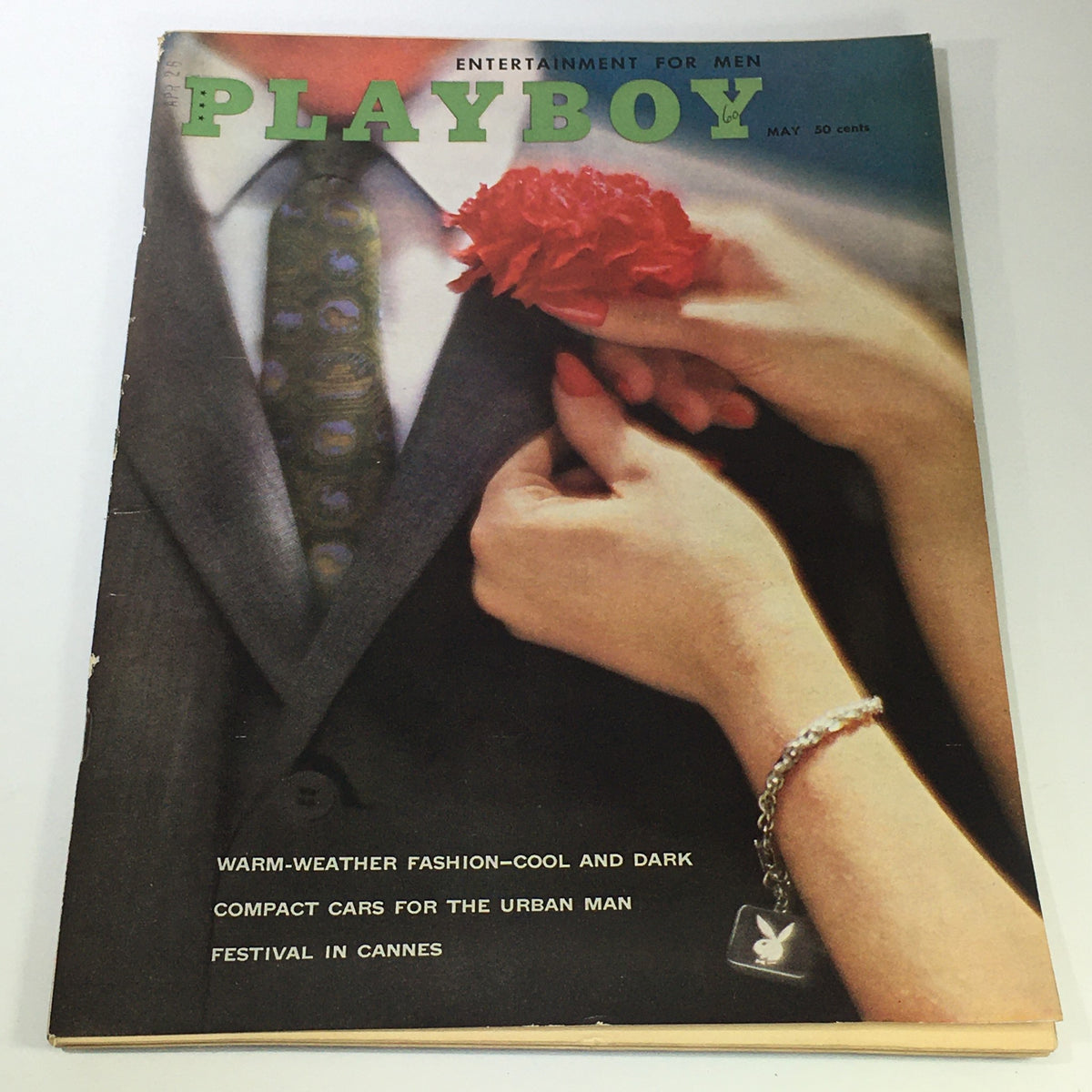 Vintage Playboy Magazine cover from May 1960 featuring the theme Festival in Cannes and Fashion Cool Dark, showcasing a man in a suit and a woman holding a flower, highlighting the glamorous 1960s fashion era.