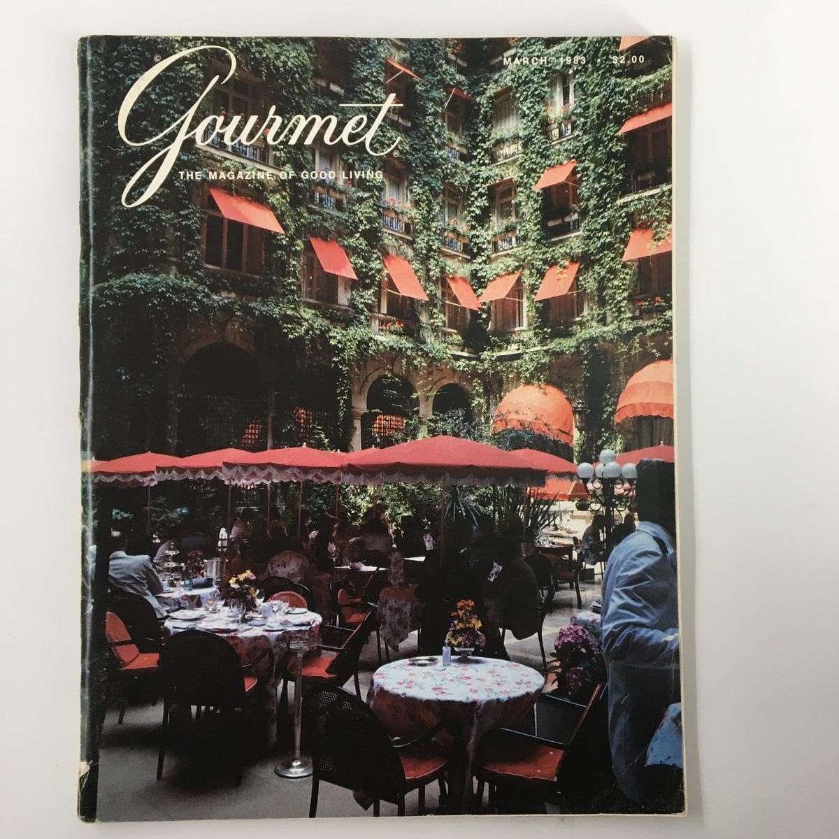 Cover of VTG Gourmet Magazine March 1983 featuring the Courtyard Garden of the Plaza-Athenee, showcasing elegant dining with red umbrellas and lush greenery.