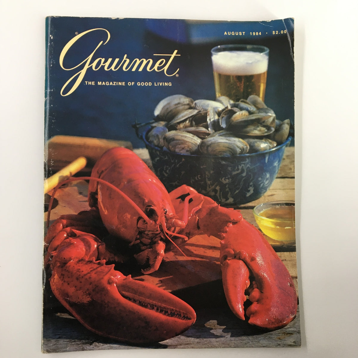 VTG Gourmet Magazine August 1984 cover featuring succulent steamed lobster and clams, showcasing a vibrant seafood dish with a beer in the background.