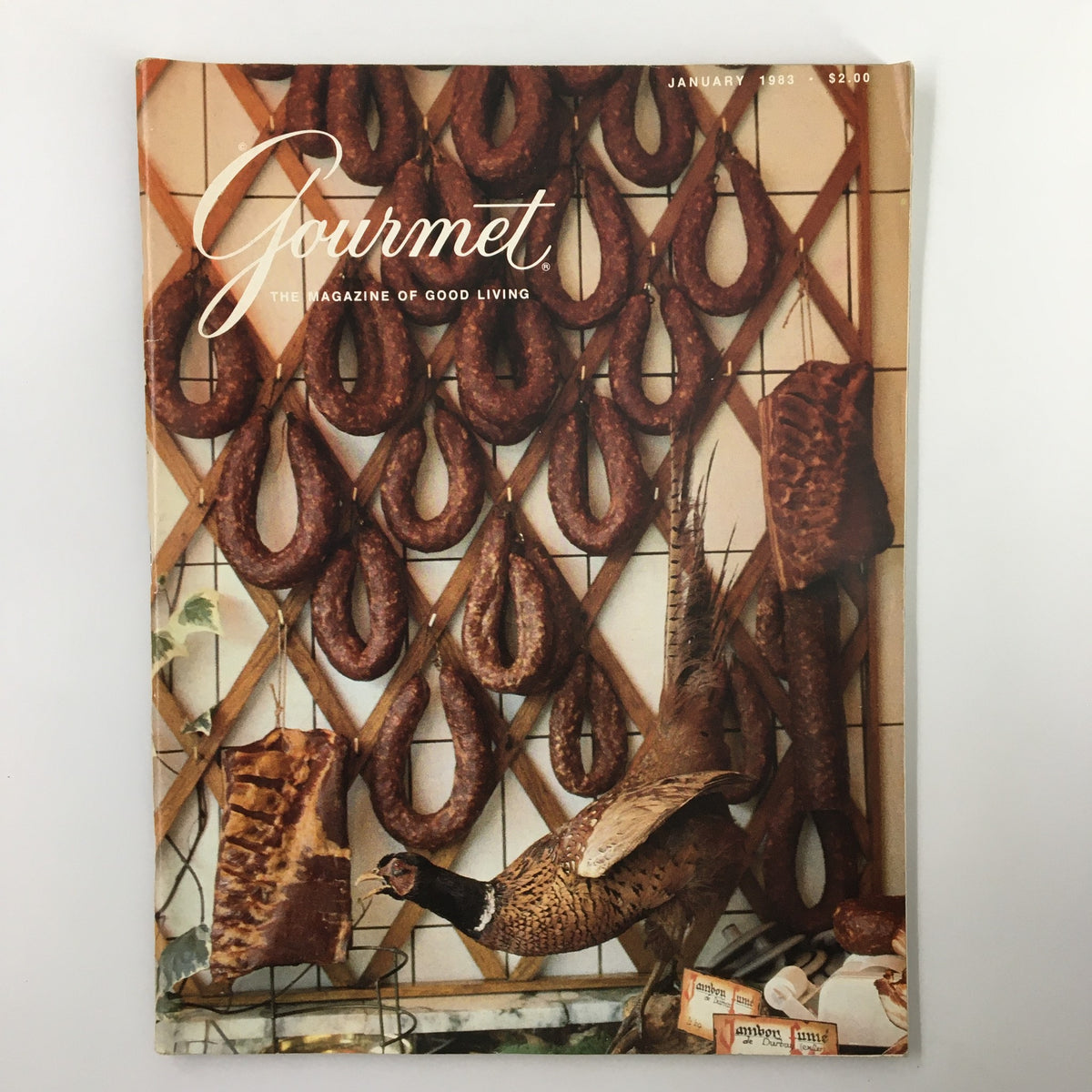 Cover of Gourmet Magazine January 1983 featuring a display of cured meats and a pheasant, part of the issue titled 'Colliers des Ardennes Festoon'.