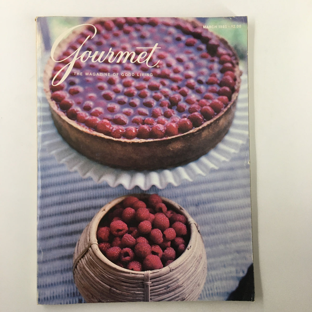 Vintage Gourmet Magazine March 1985 cover featuring a raspberry cheesecake and a basket of raspberries, showcasing themes of gourmet cooking and salad dressings.