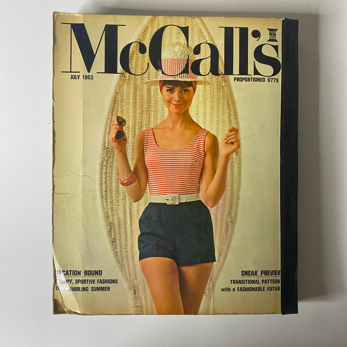 The cover of the 1963 July McCall's Summerwear Catalog featuring a woman in a striped swimsuit and hat, showcasing sporty summer fashion inspired by vacation looks.
