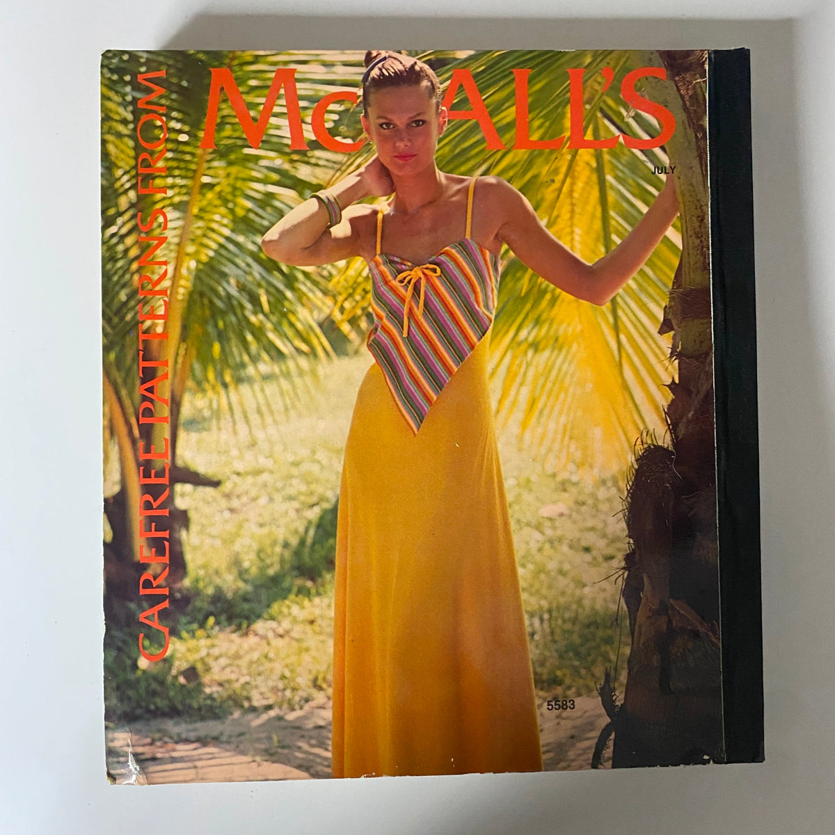 Cover of the 1977 July Carefree Patterns McCall's Catalog showcasing a model in a stylish yellow summer dress, embodying the vibrant fashion of the late 1970s.