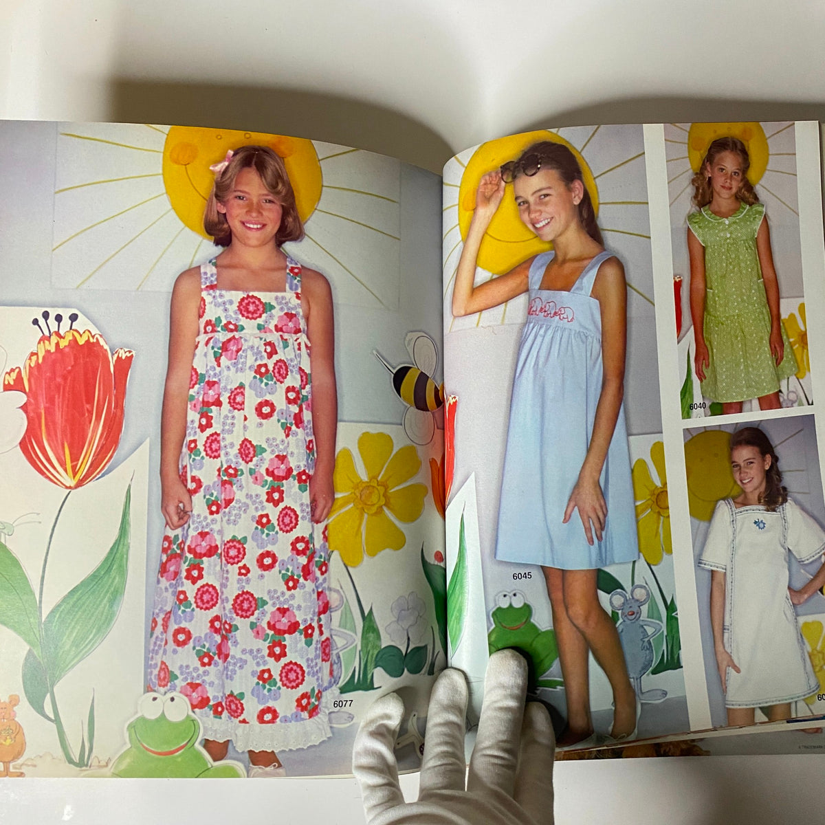 1970s June Carefree Patterns McCall's catalog page displaying young girls in colorful summer dresses against a cheerful background of flowers and sun, highlighting children's patterns.