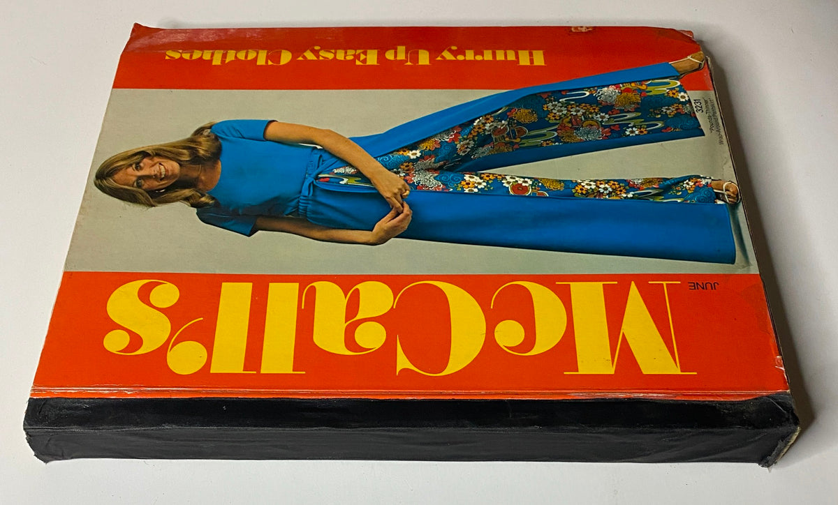 Cover of the 1970s McCall's Hurry Up Easy Clothes Catalog featuring a model in a blue dress and colorful pants, showcasing vintage fashion designs.