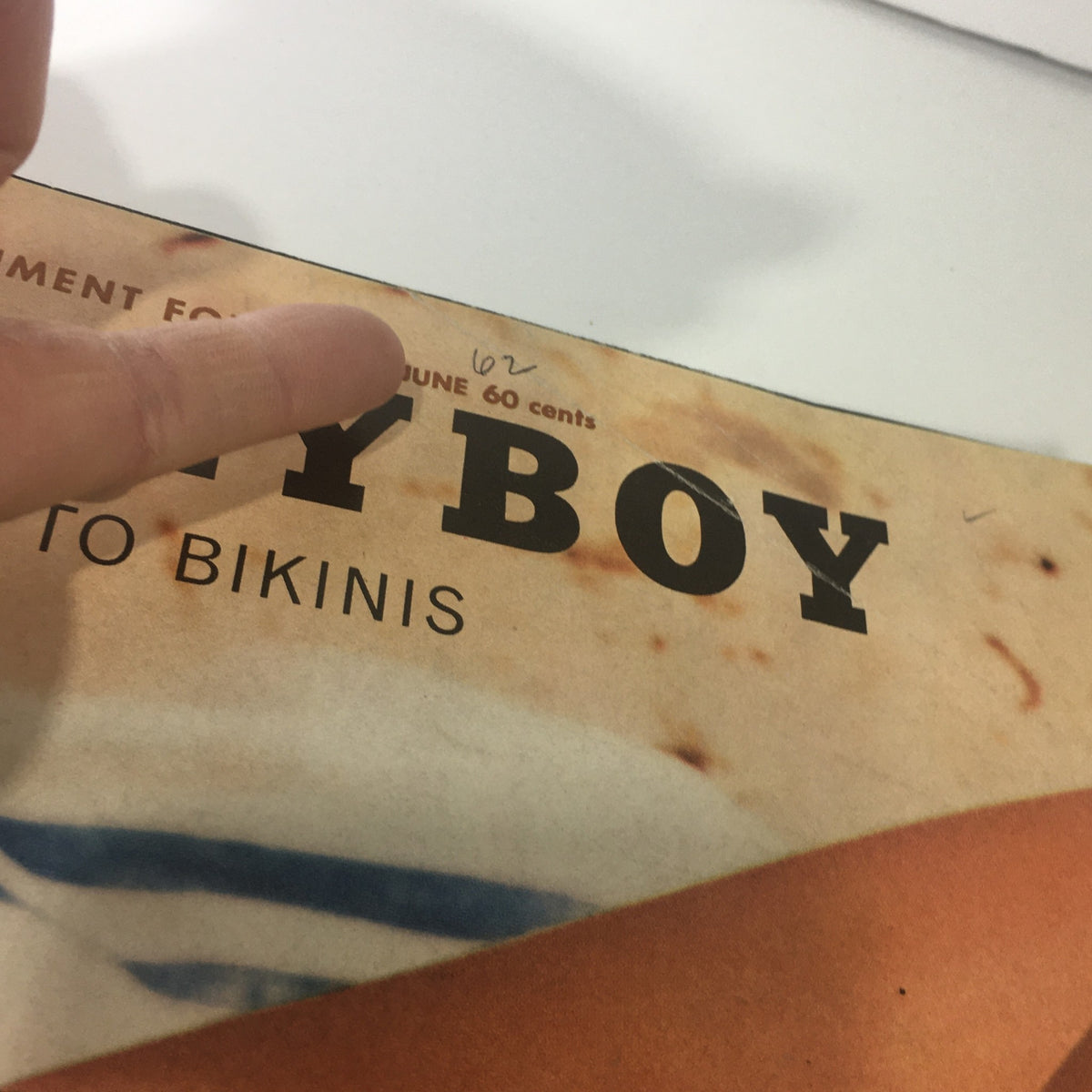 VTG Playboy Magazine: June 1962 showing the magazine title under a finger pointing at the 'June 62' date, highlighting its vintage authenticity and collectible nature.