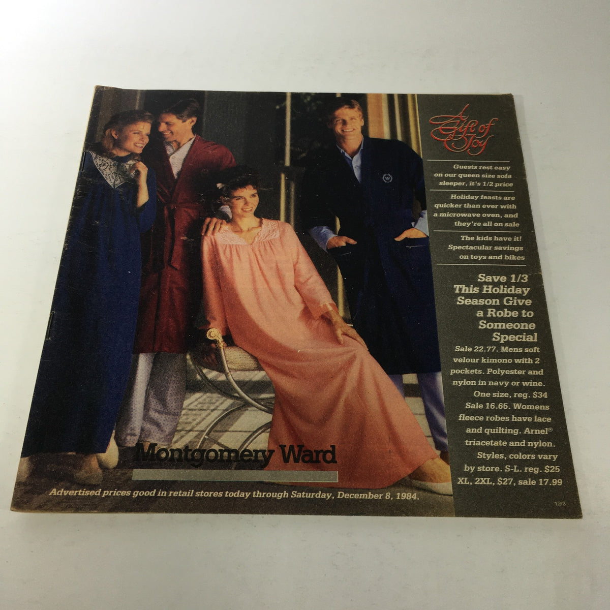 VTG Montgomery Ward Store Catalog: December 1984 cover featuring models wearing holiday robes, showcasing a relaxed festive atmosphere, along with promotional text for gift ideas and discounts.