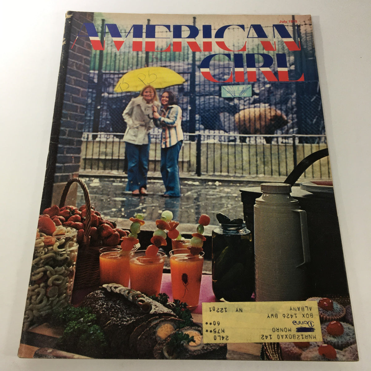 Vintage American Girl Magazine July 1973 cover featuring two girls under a yellow umbrella with refreshments displayed in the foreground.
