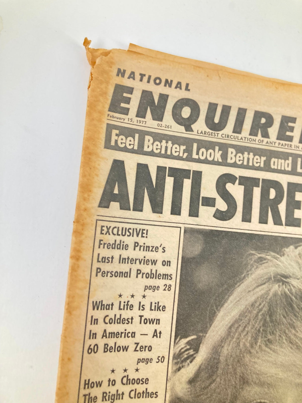 Close-up of the National Enquirer Tabloid from February 15, 1977, showing the headline 'ANTI-STREET' and a corner tear, featuring Farrah Fawcett and Lindsay Wagner.