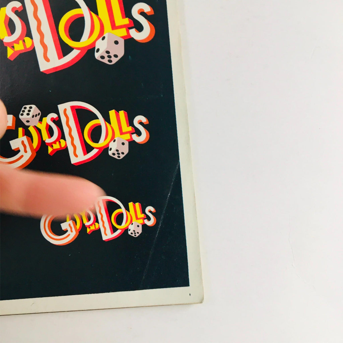 Close-up view of the 1992 Guys and Dolls Playbill at Jerry Zaks showcasing its colorful cover with distinctive typography and dice graphics.