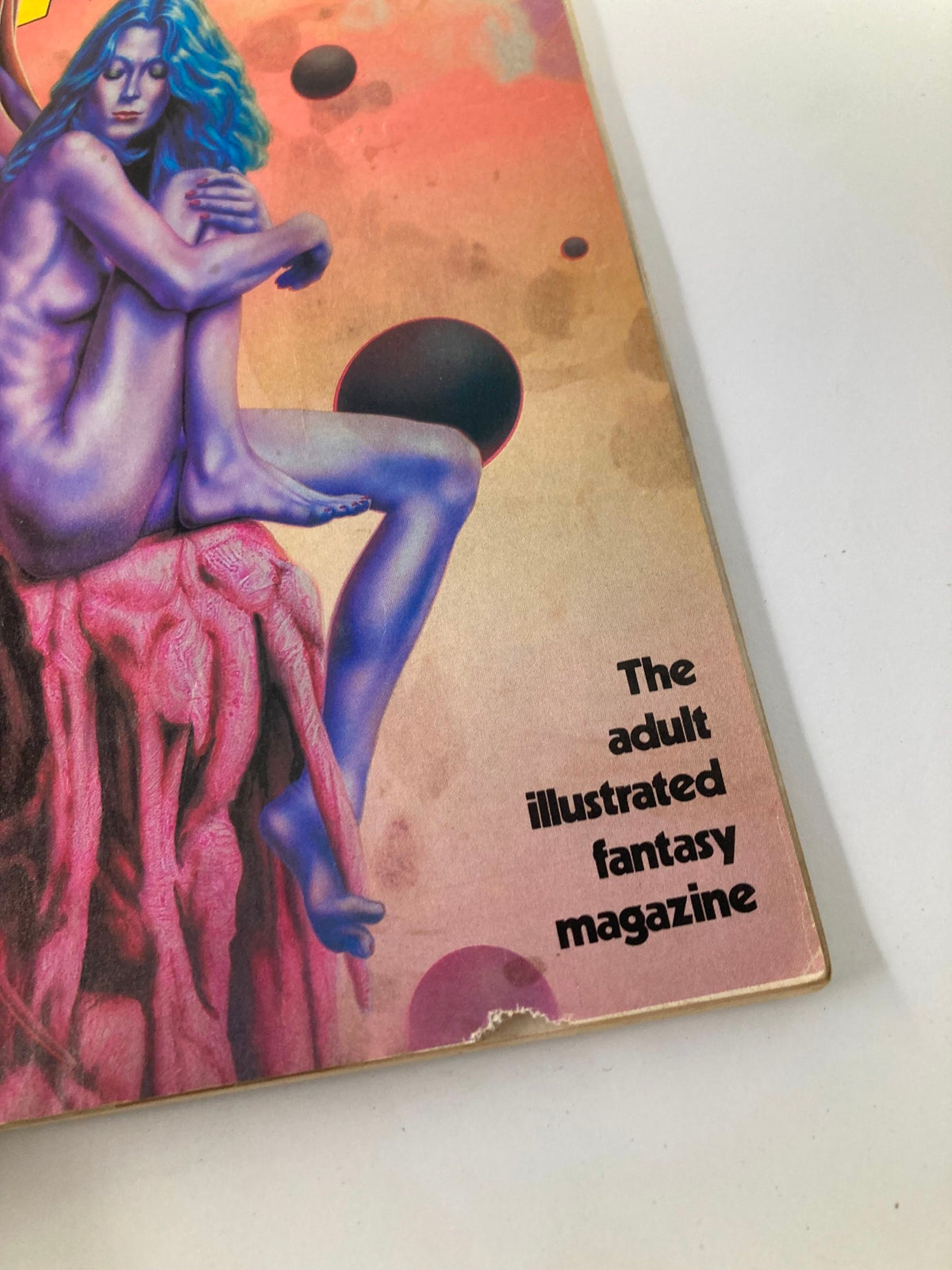 Detailed view of the bottom edge of the VTG Heavy Metal Magazine June 1983 Vol 7 #3 showing the text 'The adult illustrated fantasy magazine' alongside artistic imagery, capturing the essence of 1980s graphic culture.