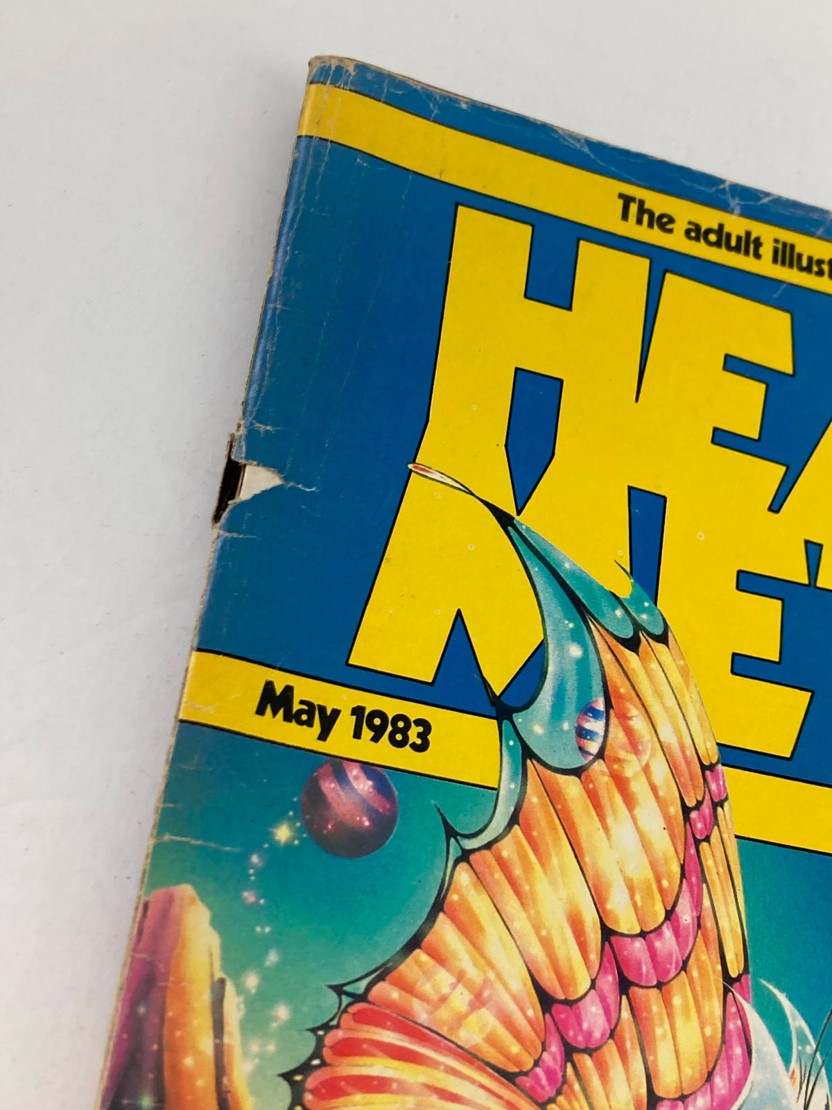 Close-up of the corner of VTG Heavy Metal Magazine May 1983 Vol 7 #2 showing minor wear and details of the vibrant front cover illustration.