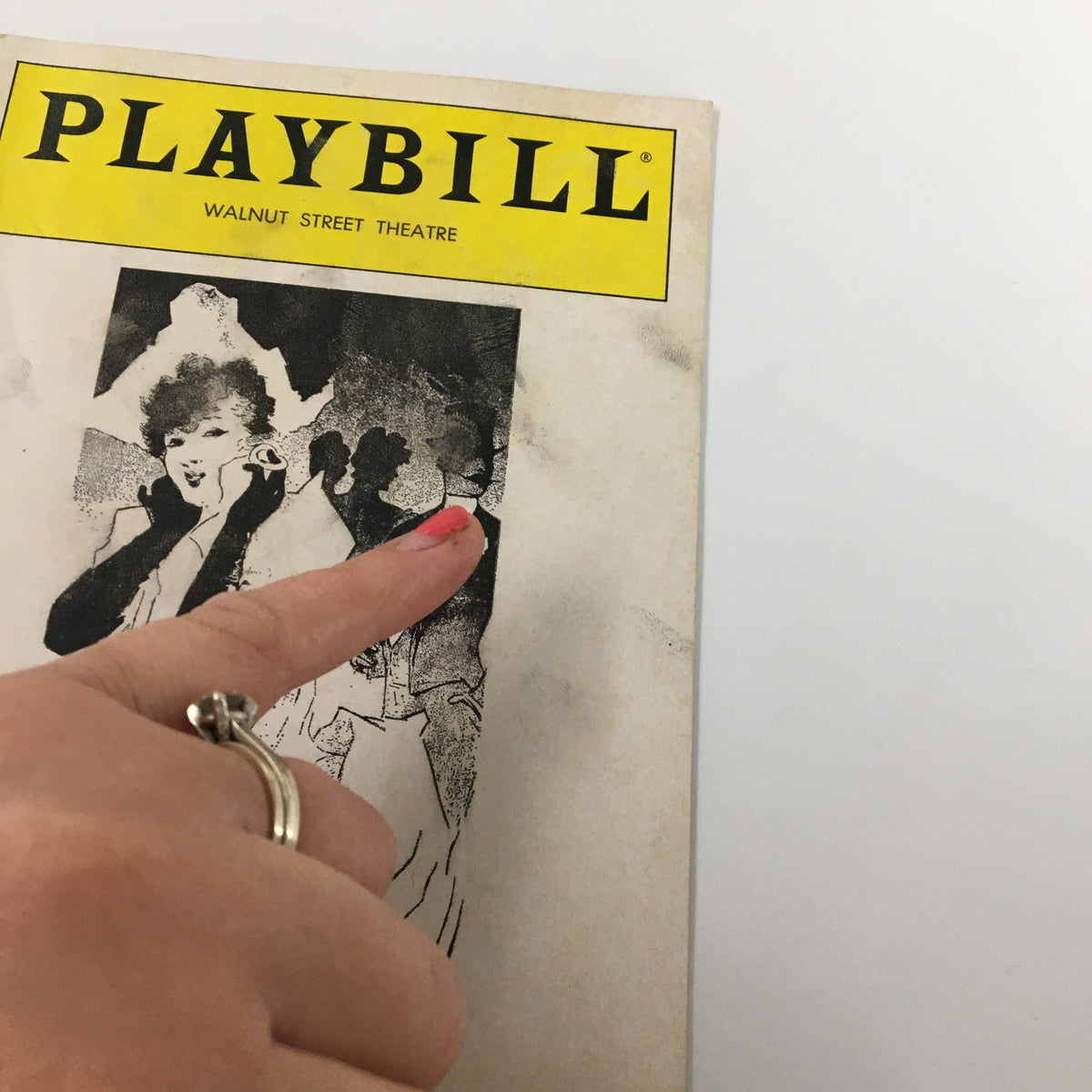 Close-up of the front cover of the 1982 Playbill for 'A Flea in Her Ear' by Donald Ewer, highlighting details of the artwork and the wear reflecting its history.