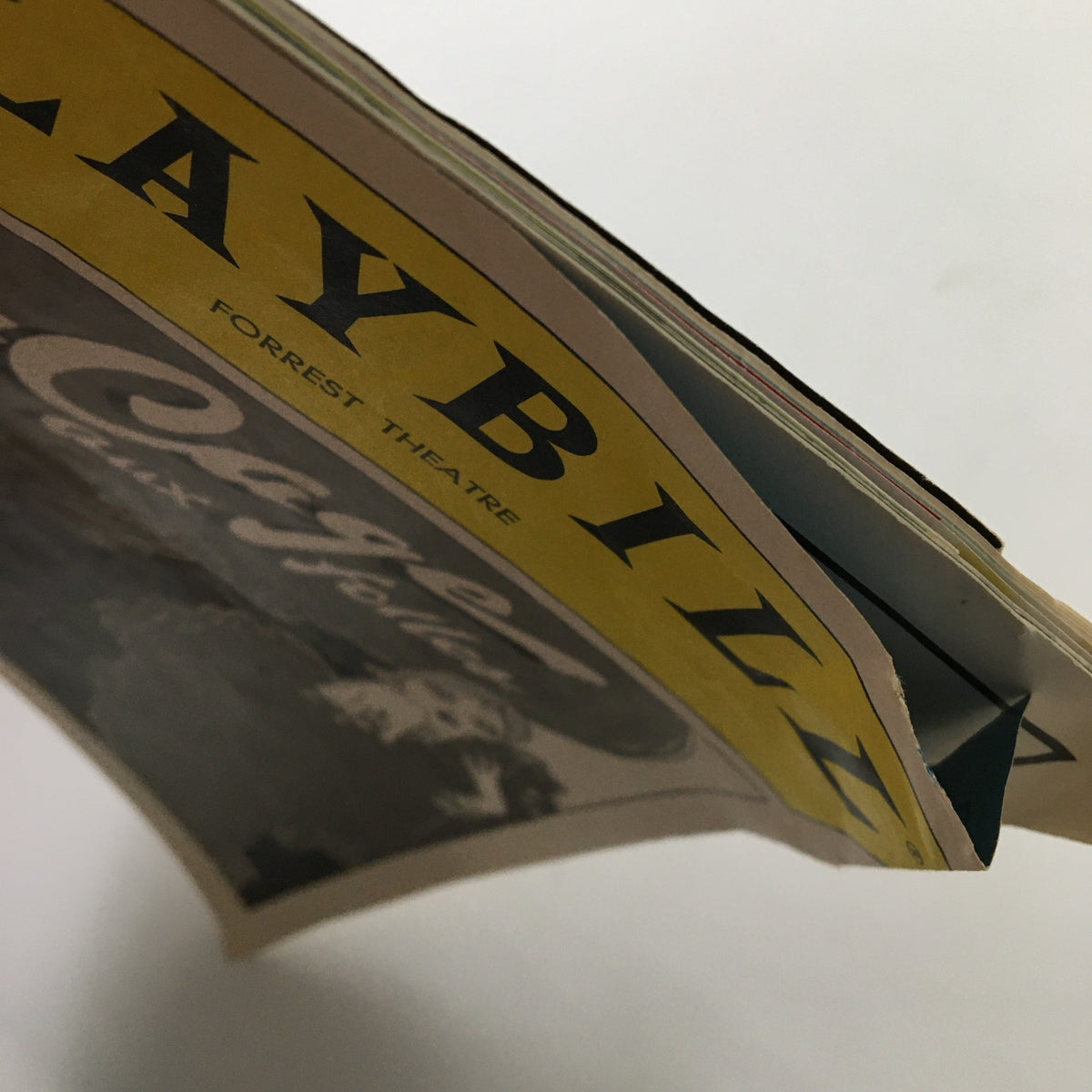 Side view of the 1983 Playbill for La Cage Aux Folles, highlighting the textured edges and layers of the Playbill.