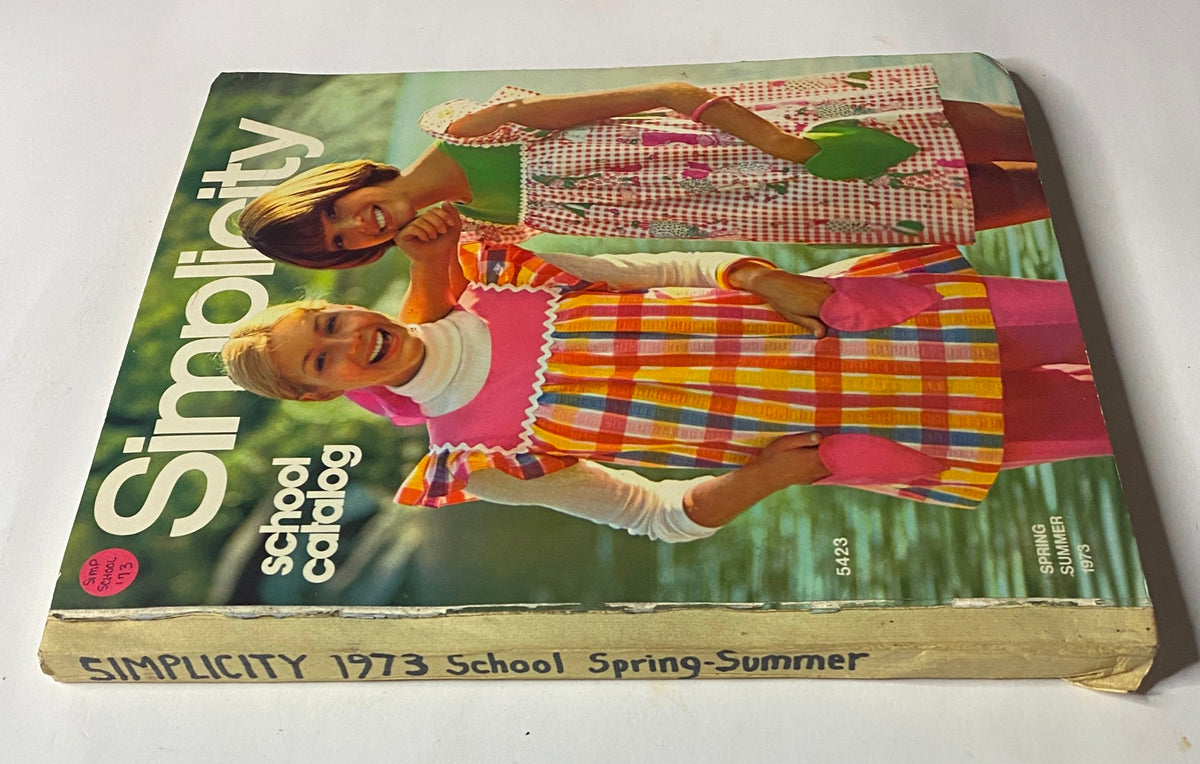 Close-up view of the 1973 Simplicity Spring Summer School Catalog cover, highlighting two young girls in vibrant dresses, emphasizing the playful fashion styles of the 1970s.