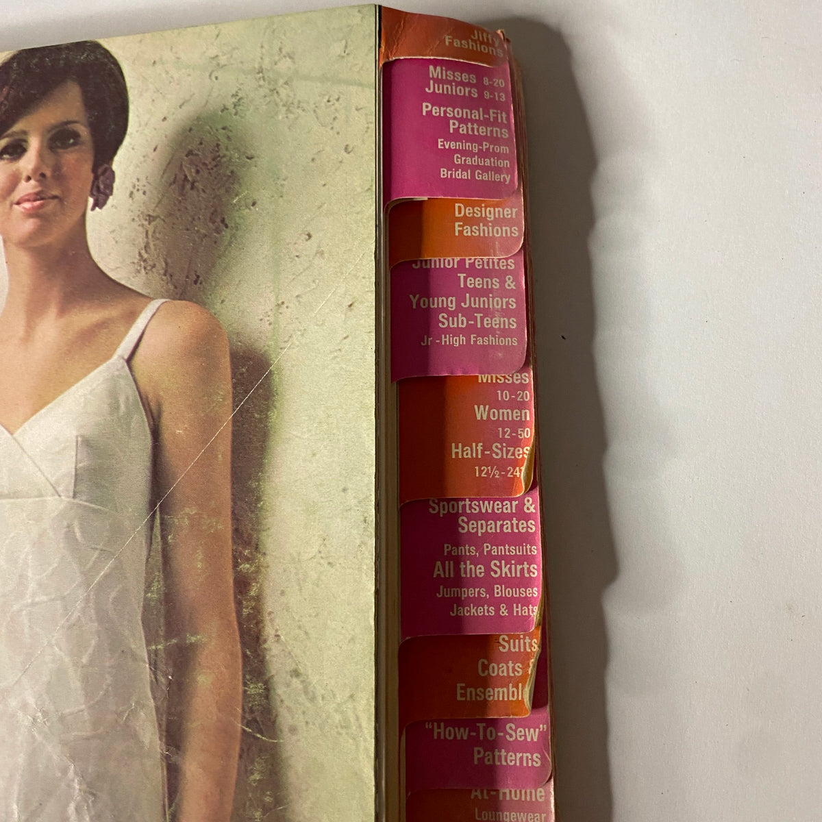 Detailed view of the spine of the 1967 June Simplicity Sewing Pattern Catalog, showcasing various categories including Misses’, Juniors, Personal-Fit Patterns, and Designer Fashions.