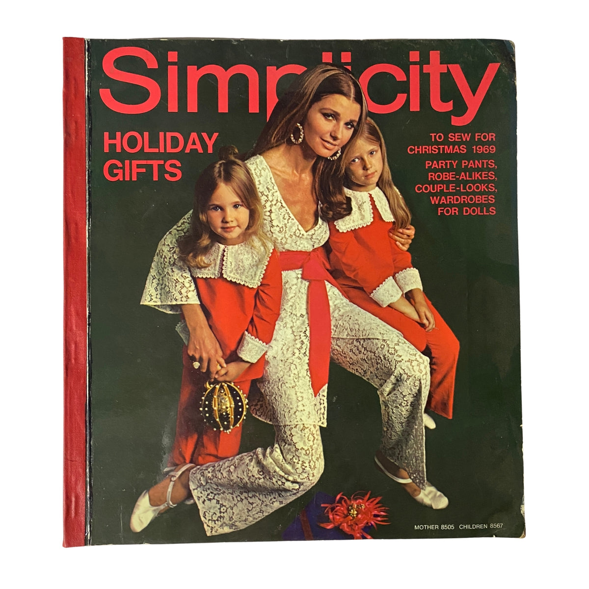 1969 Simplicity Holiday Catalog featuring a vintage cover with a woman dressed in a lace outfit alongside two children in festive red outfits, showcasing holiday gift ideas for sewing, including doll wardrobes and seasonal fashions.
