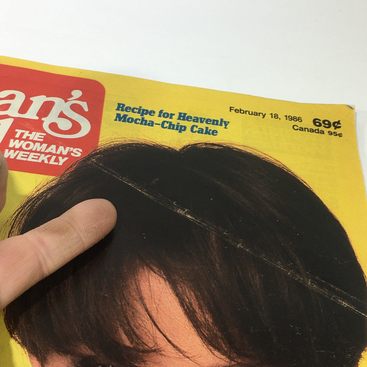 Close-up of the cover of VTG Woman's World Magazine from February 18, 1986. Focus on the title and a woman's hairstyle, showcasing retro magazine design and features like recipes and business fashion.