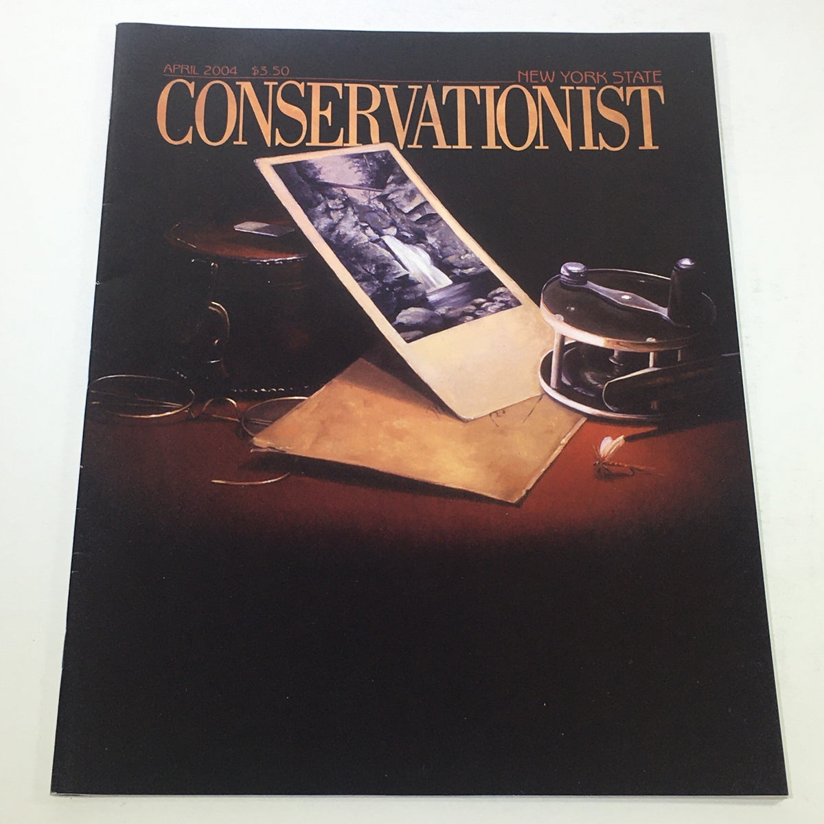 VTG New York State Conservationist: April 2004 cover featuring a retro photograph with an old-style layout and vintage elements such as an open magazine and antique tools.