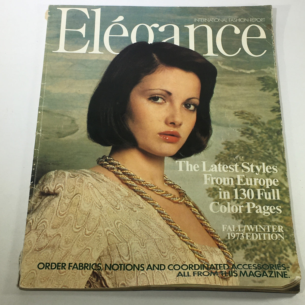 Elegance Magazine: Fall-Winter 1973 Edition cover showcasing a model with a chic bob hairstyle, wearing a fashionable cream-colored outfit and statement necklace, promoting the latest styles from Europe in 130 full-color pages.