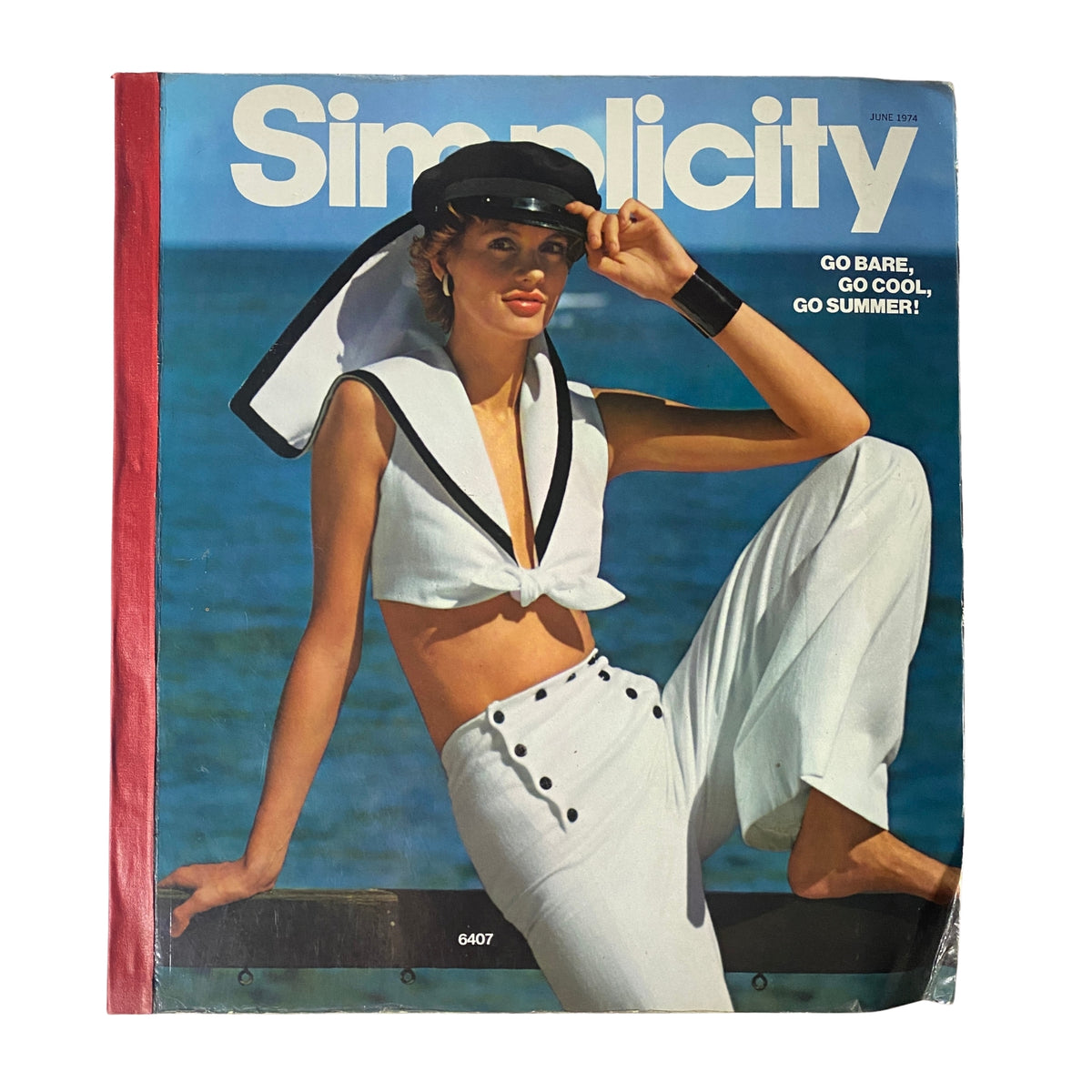 Cover of the 1974 June Simplicity Catalog showcasing summer fashion. The model in a stylish sailor outfit poses against a beach backdrop. Perfect for sewing enthusiasts and vintage fashion lovers.