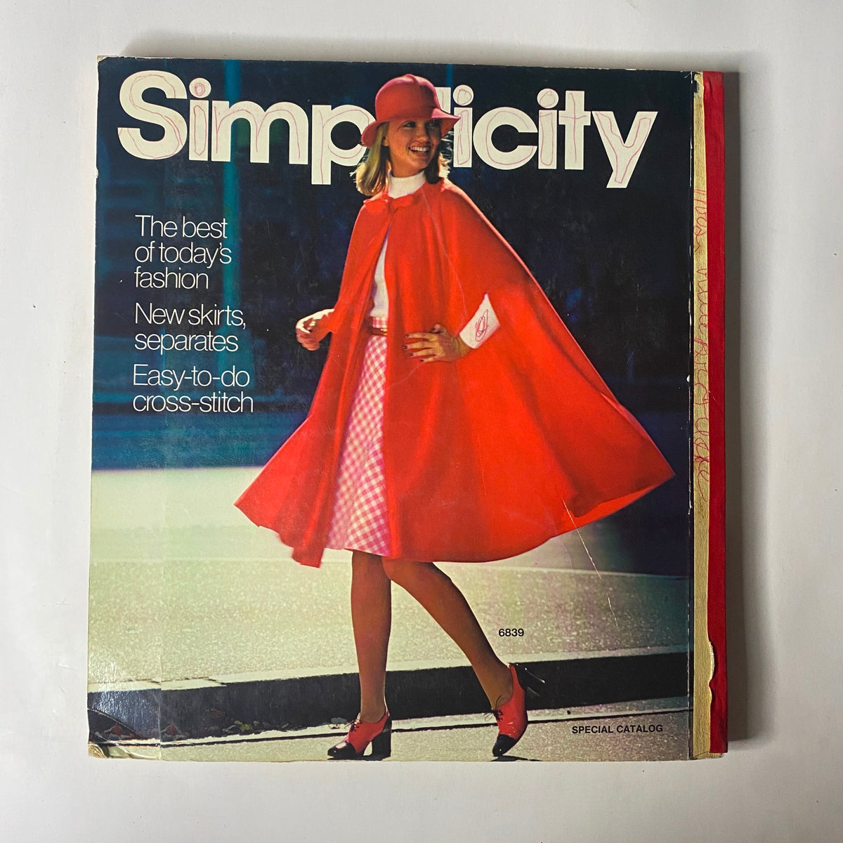 1975 Simplicity Special Catalog cover featuring a fashionable model in a vibrant red cape and skirt, highlighting the best of mid-1970s fashion and sewing patterns.