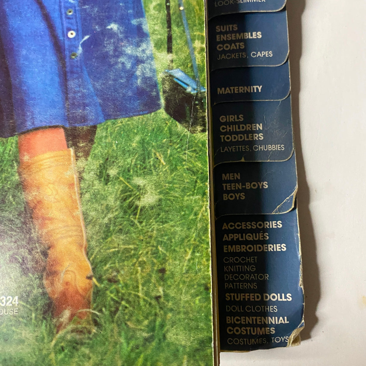 1976 March Simplicity Catalog showcasing a sewing pattern cover with a woman in a blue dress and brown boots, highlighting various sewing categories such as maternity and children’s wear.