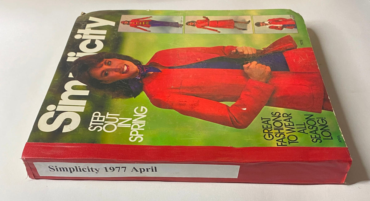 Side view of the 1977 April Simplicity Sewing Pattern Catalog with the title shown on the spine. The cover features a smiling woman in a vibrant red outfit.