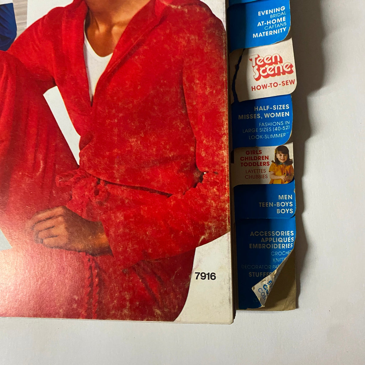 1977 March Simplicity Sewing Pattern Catalog Store Counter Book cover featuring a model in a red outfit, highlighting the catalog's fashion focus.