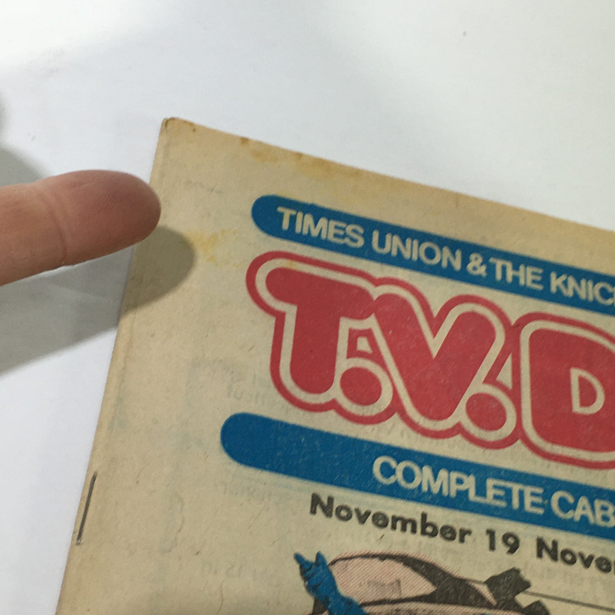 Close-up view of the VTG TV Dial Complete Cable Listings November 19-26 1977, showing the title and a finger pointing at the cover.