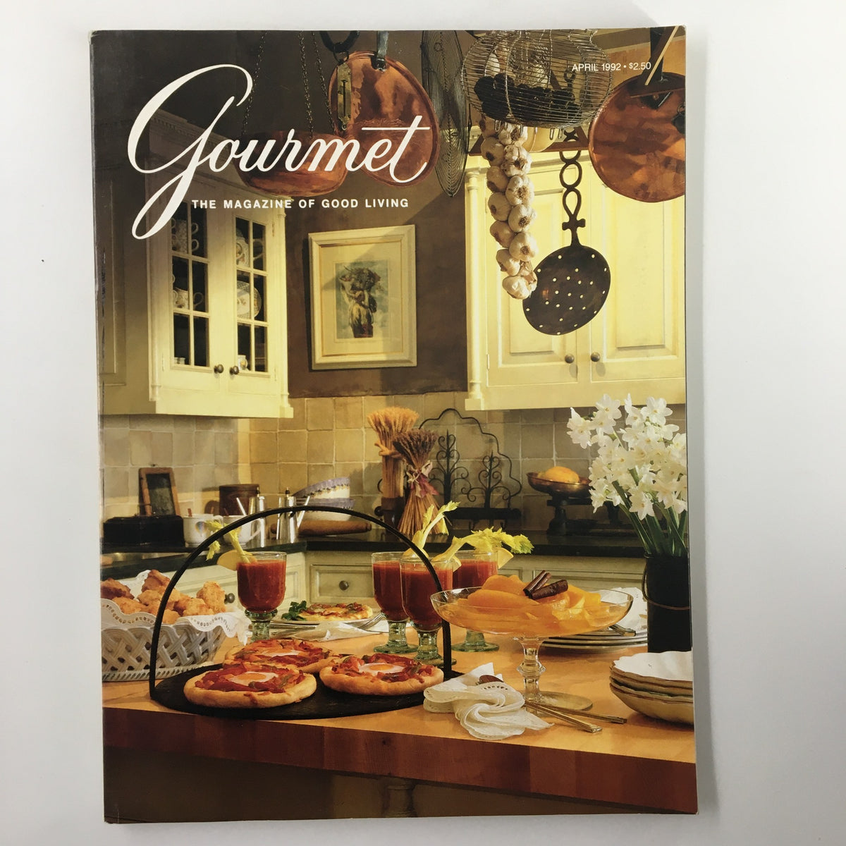 Cover of Gourmet Magazine April 1992 featuring a kitchen scene with sun-dried tomatoes, reflecting the theme of good living and gourmet culinary experiences.