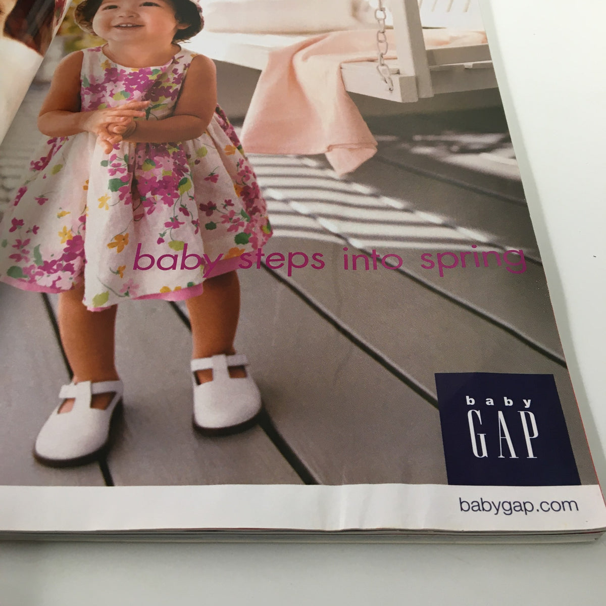 Advertisement from BabyGap showcasing a child in a spring floral dress, evoking themes of seasonal fashion for children.