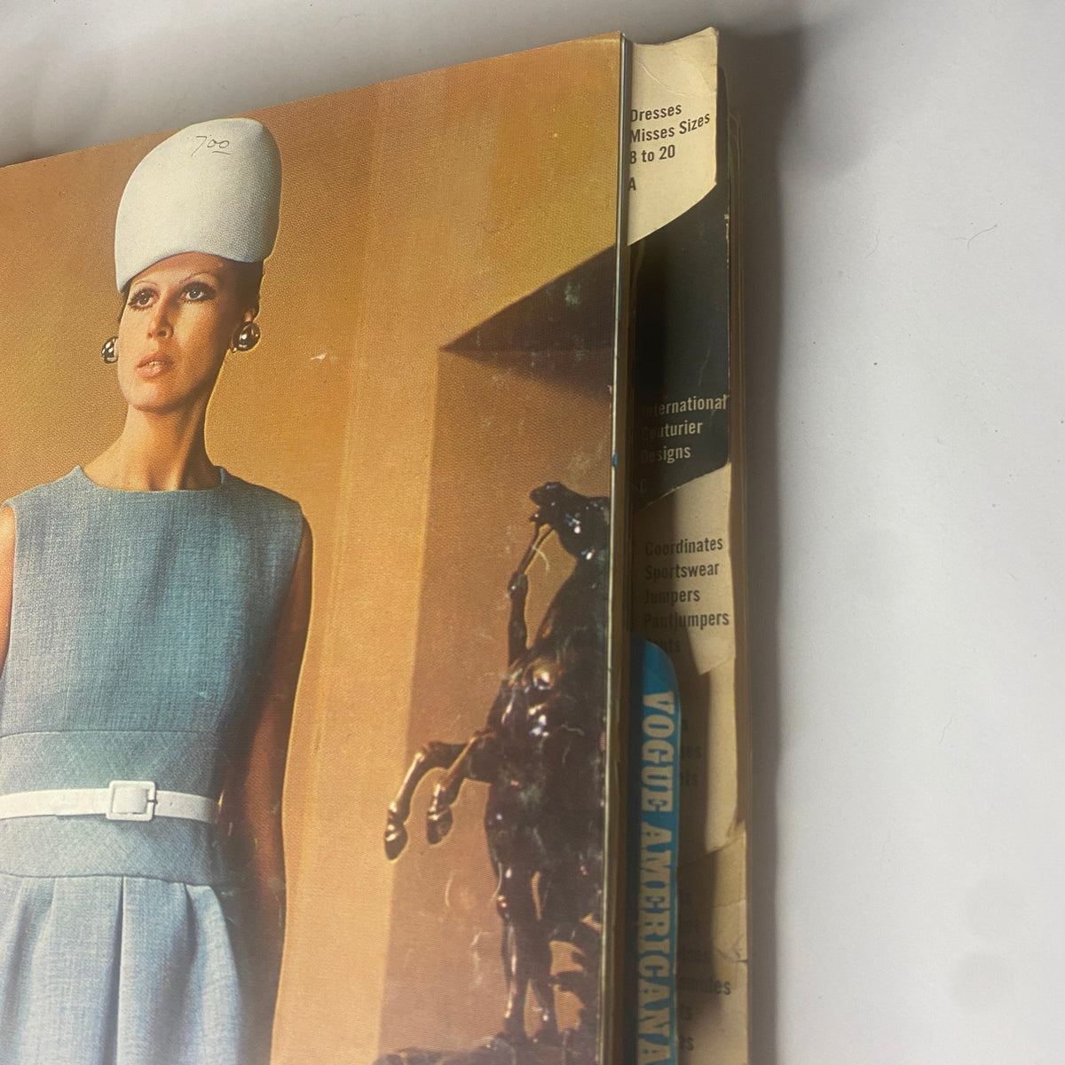 Close-up view of the 1969 Vogue Patterns July Catalog Large Store Counter Pattern Book illustrating a model in a blue dress with a sleek hat. Captures the elegance and sophistication of 1960s fashion design.