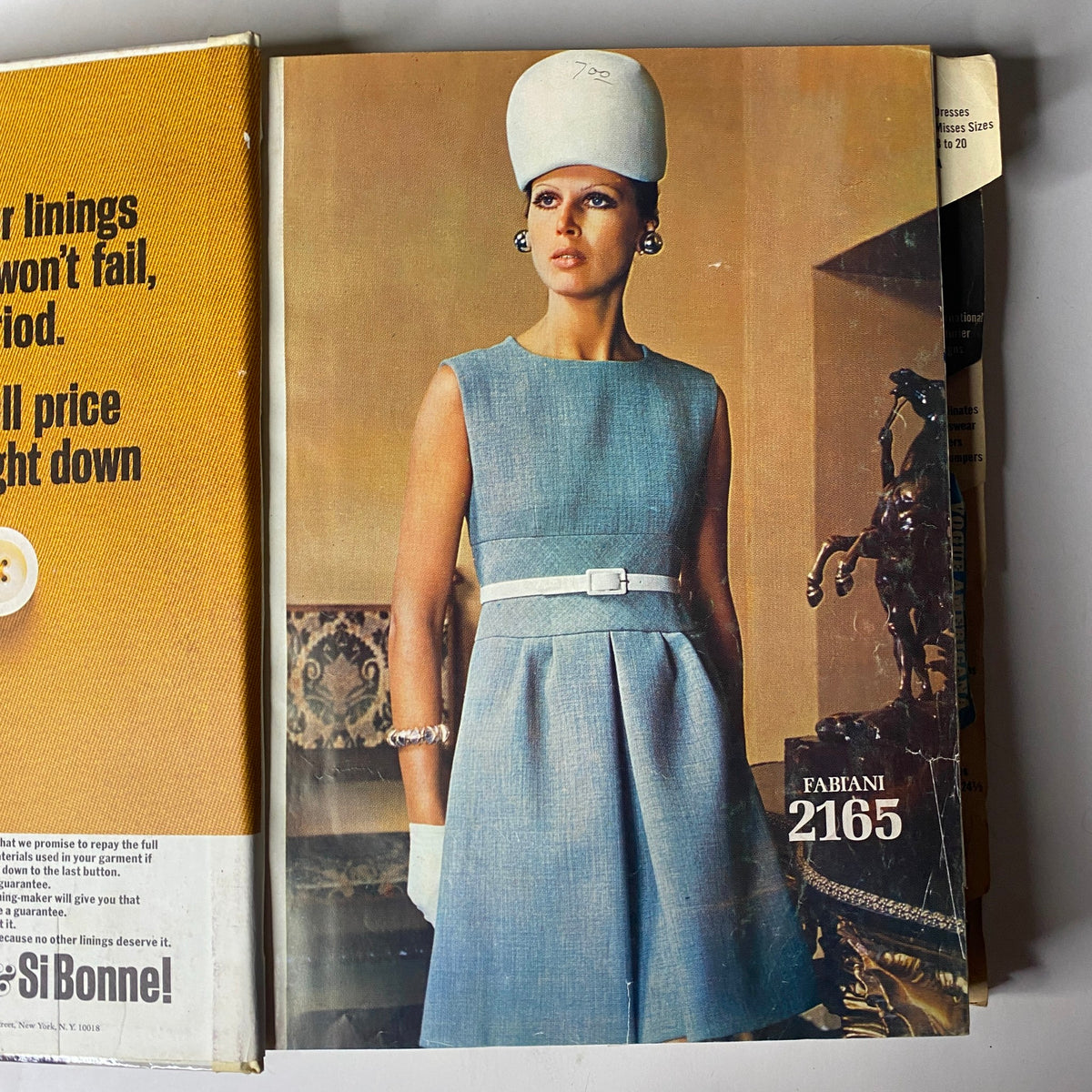 Alternate cover view of the 1969 Vogue Patterns July Catalog featuring a woman modeling a blue dress and large white hat, underlining the elegant designs of the era.