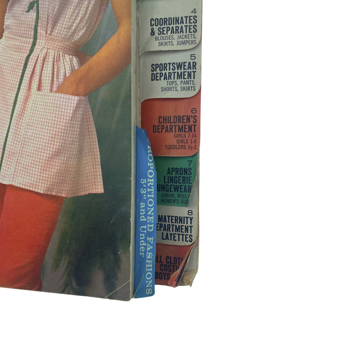 Details of the 1961 December Butterick Holiday Catalog with a close-up of department labels featuring styles for various age groups and clothing categories.