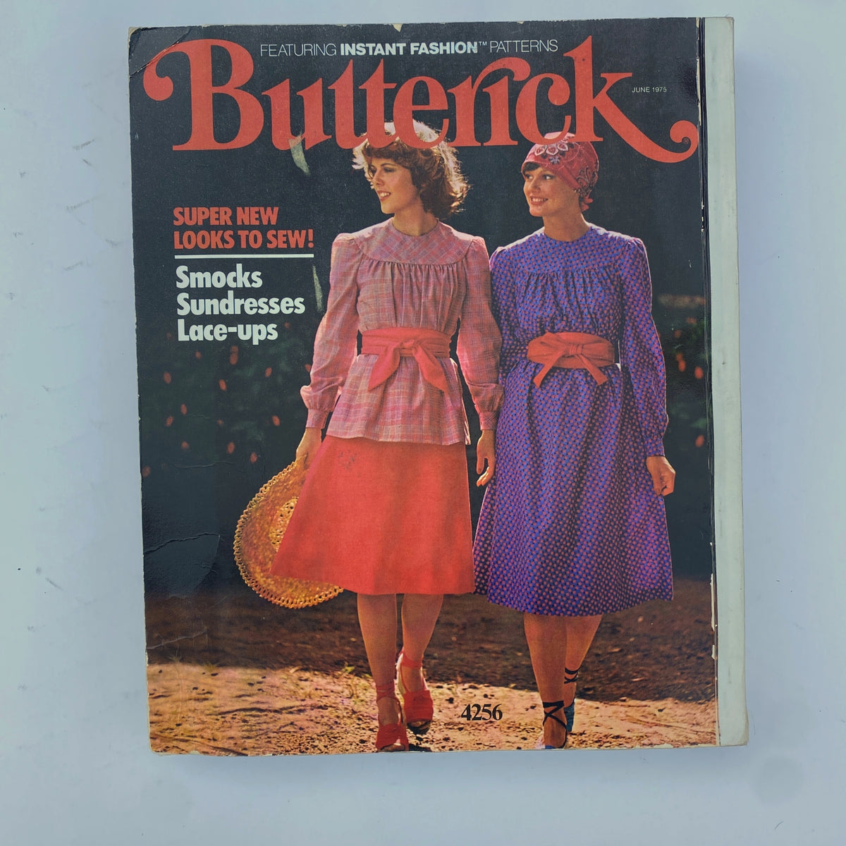 1975 June Butterick Catalog cover featuring two women in vibrant smocks and sundresses, highlighting fresh summer sewing styles and eye-catching fashion.
