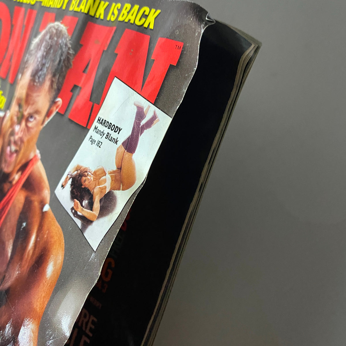 Close-up of Iron Man Magazine December 2010 showing corner damage and a feature on Mandy Blank. Authentic detail of the magazine's condition showcased.